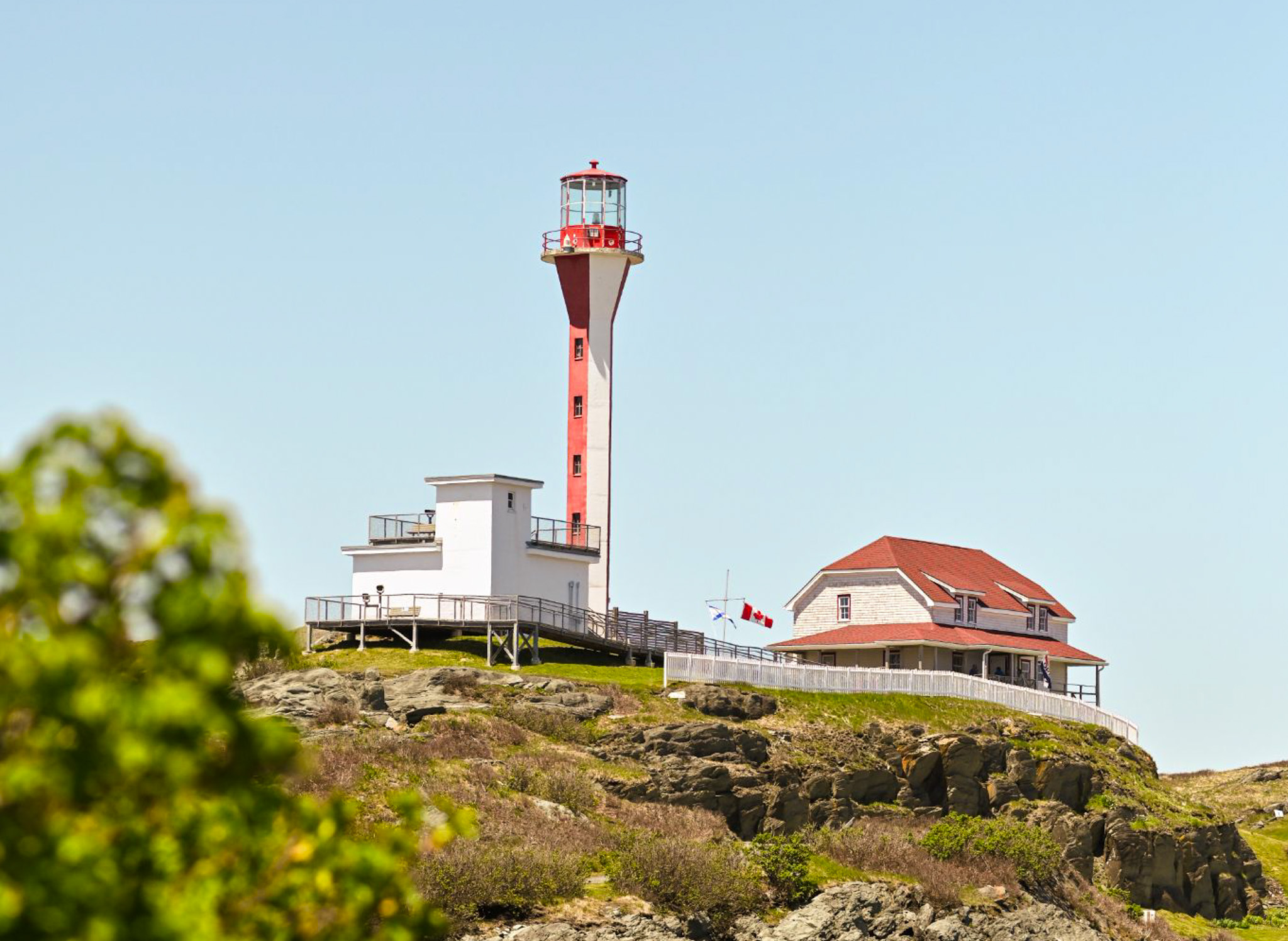 image of a apple core red and white lighthouse on a rocky hill.