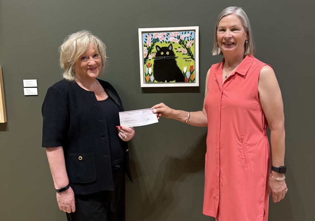 image of two women holding a cheque and smiling. One in a black outfit and the other in a pink dress.